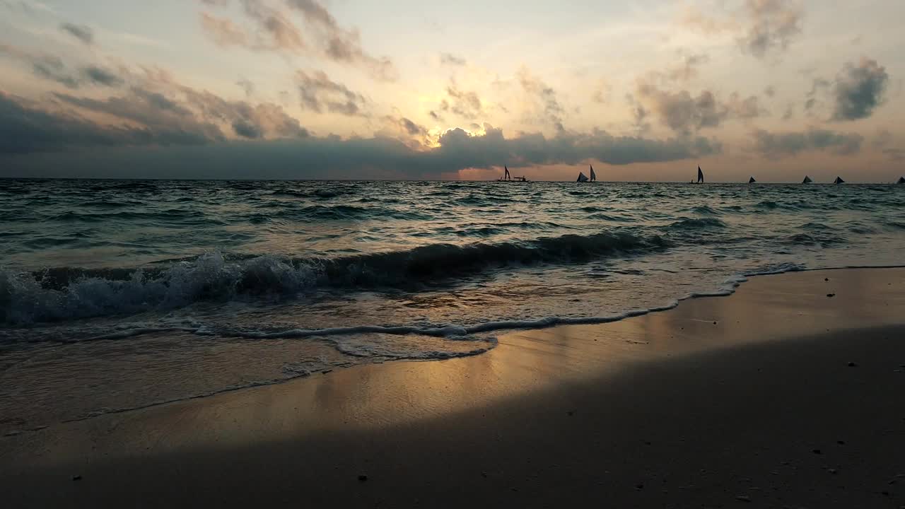 海浪拍打着沙滩。阳光反射在水面上。美丽的傍晚自然海洋背景。慢动作镜头。长滩岛,菲律宾。视频素材