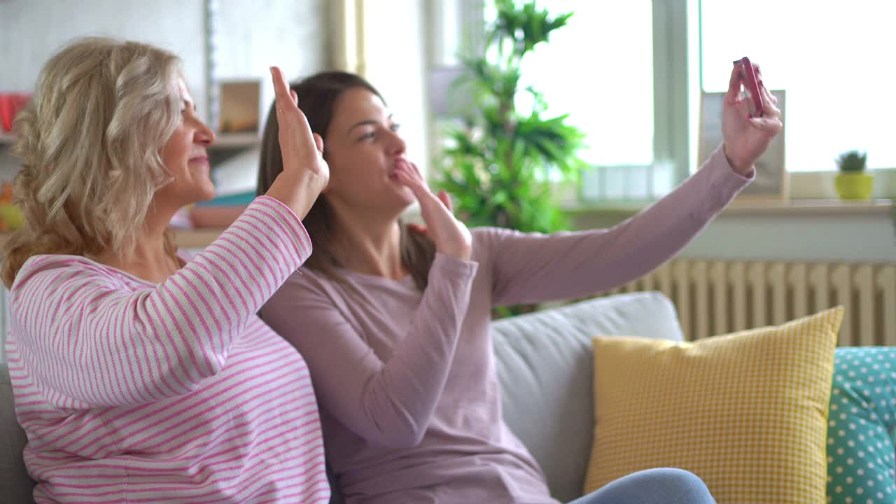 母亲和女儿在家里用智能手机打视频电话视频素材