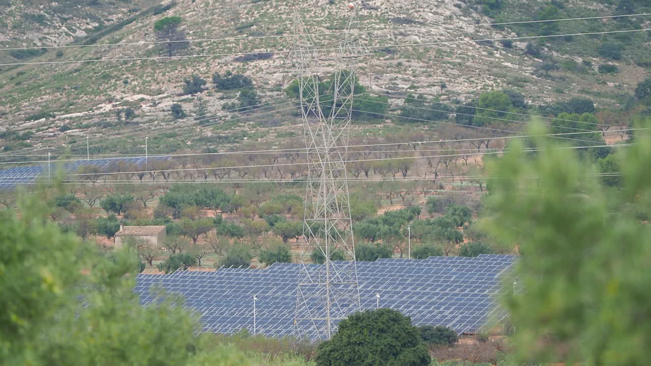 田间的太阳能电池板带有高压电塔。视频素材