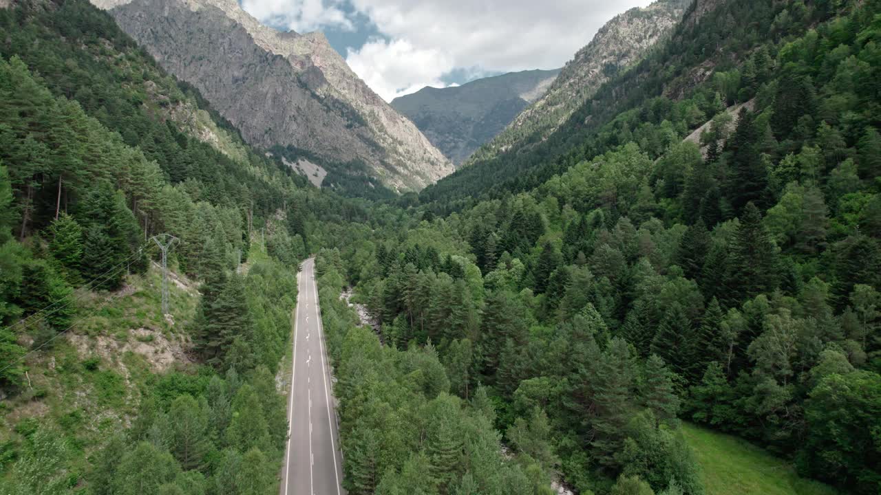 柏油路在一个山谷的高山。在它旁边，一条山间河流在树木之间蜿蜒流过。视频素材