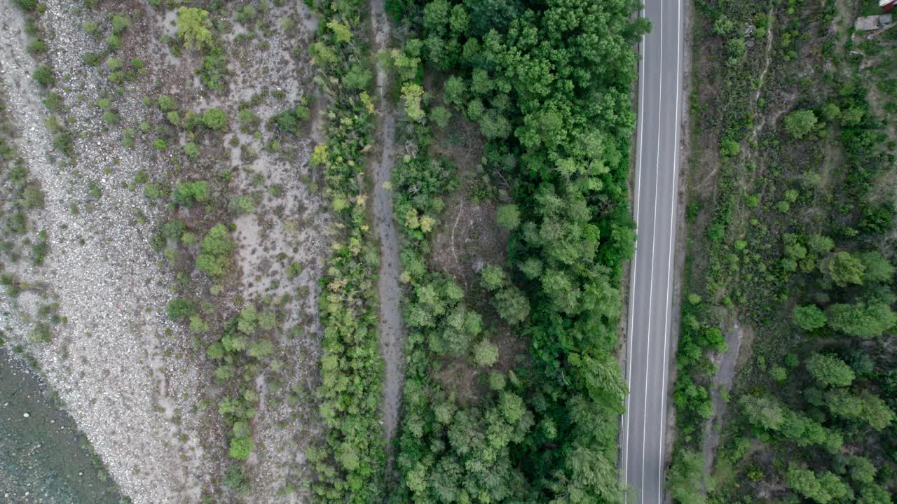 山河沿路而下的俯视图。河流与公路并排运输，绿林与石岸。视频素材