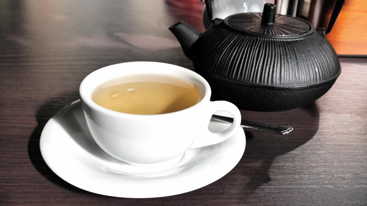 木桌上的绿茶杯和壶视频素材