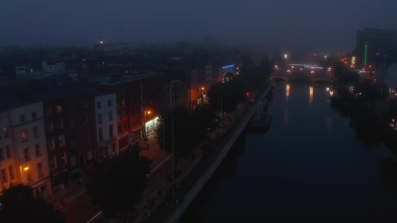 在雾蒙蒙的傍晚，船头在利菲河上空飞行。鸟瞰图的适度照明的海滨。爱尔兰都柏林视频素材