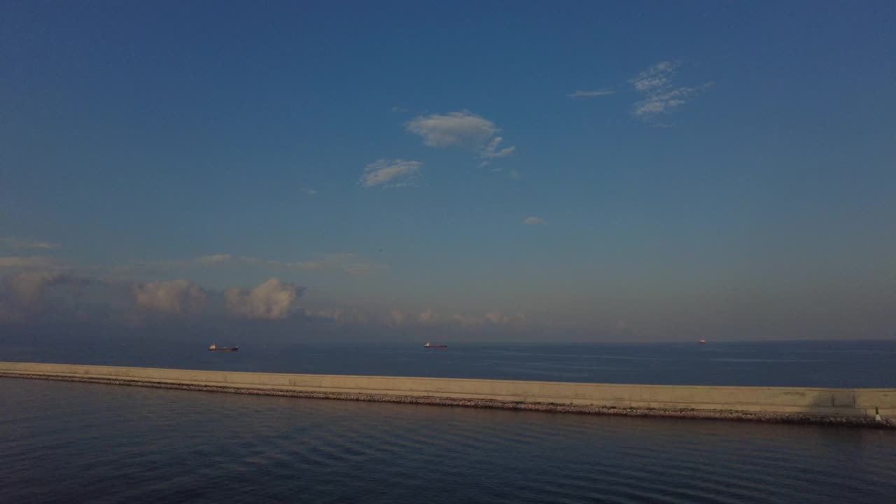 巴塞罗那港口的防波堤，背景是商船，天空中有一架飞机视频素材