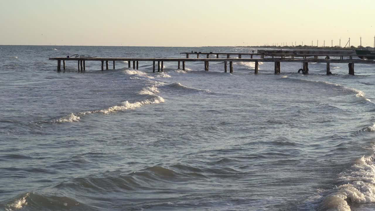 晚上美丽的海景。眺望古老的码头，波涛汹涌的大海，日落时的沙滩，海鸥在飞翔。海的地平线，海洋。沙滩,海岸线。视频素材