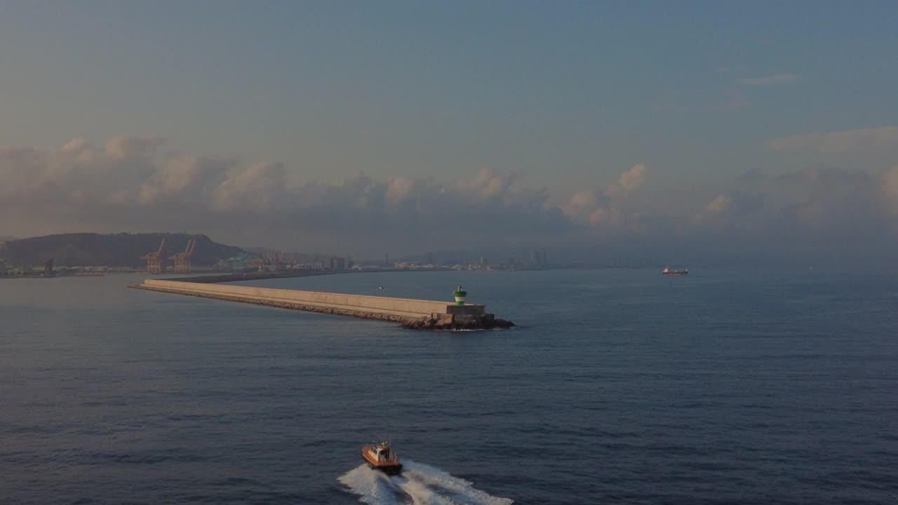 巴塞罗那港口的防波堤，背景是商船，天空中有一架飞机视频素材