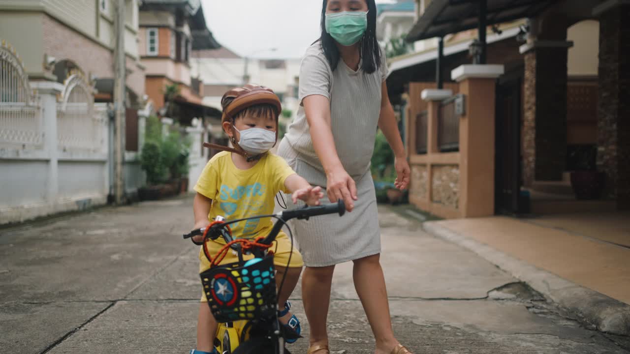 妈妈帮她的儿子第一次骑自行车。视频素材