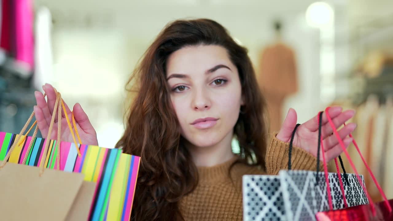 图为，在购物中心的服装店，一位漂亮的女士拿着购物袋在室内散步。视频素材