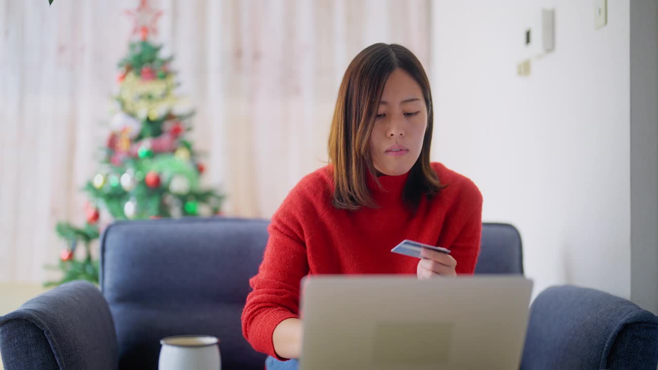 一名年轻女子圣诞节在家用笔记本电脑网购视频素材