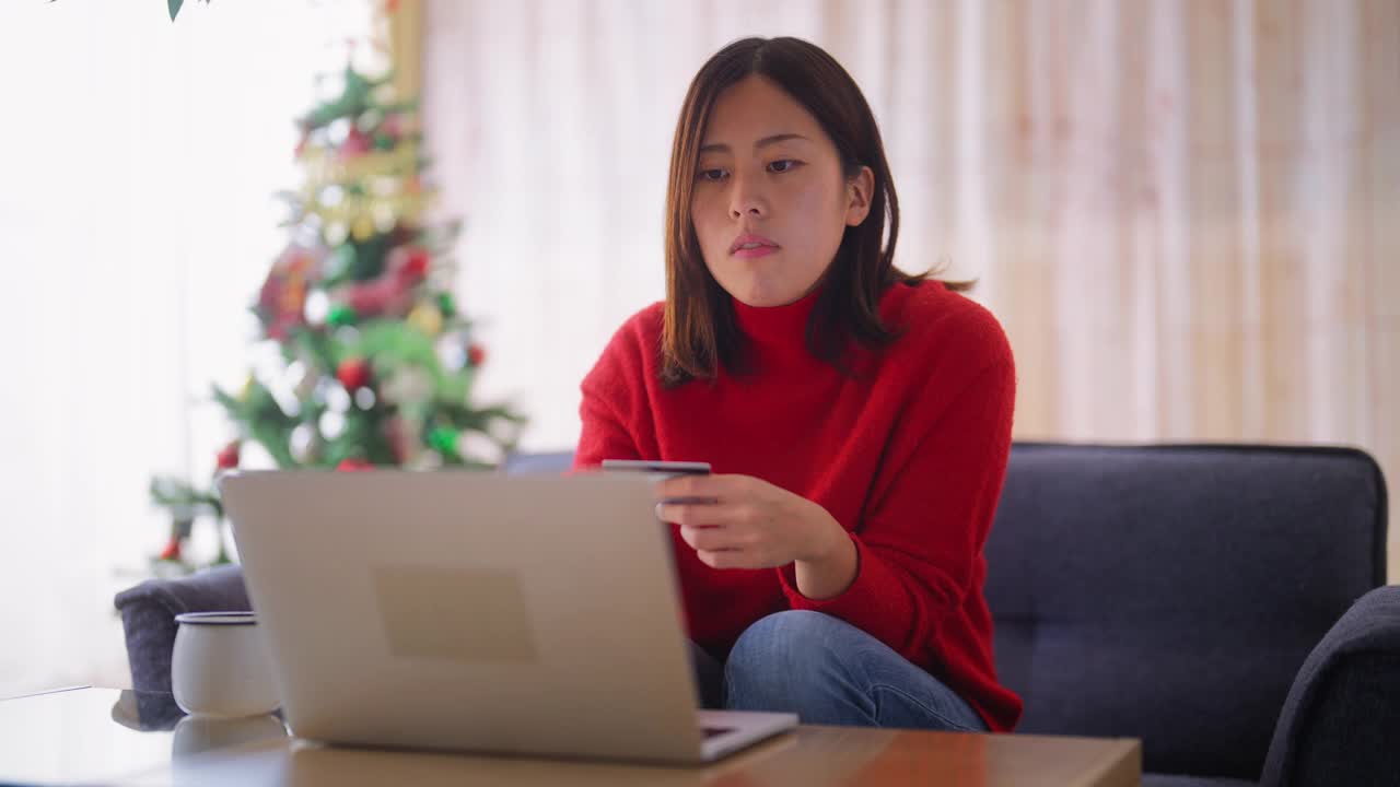 一名年轻女子圣诞节在家用笔记本电脑网购视频素材