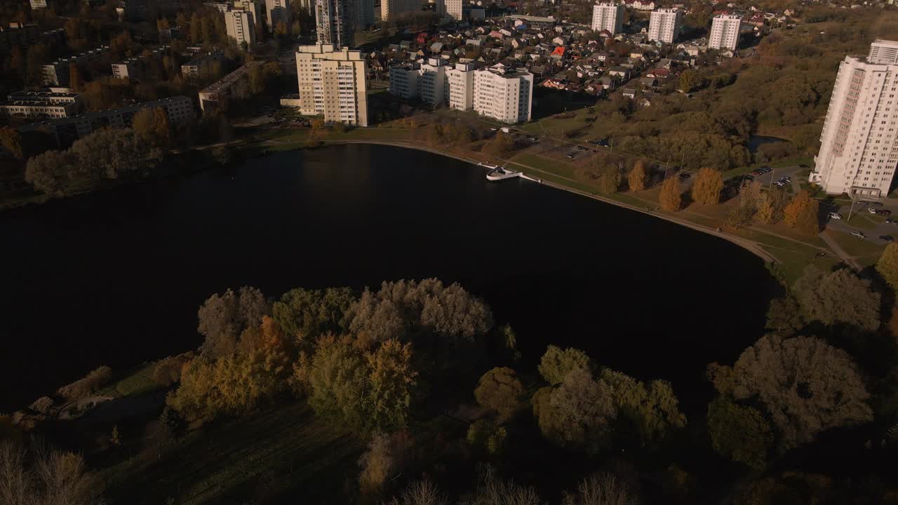 飞越秋天的公园。秋叶黄黄的树木随处可见。在地平线上有蓝色的天空和城市的房屋。公园的湖面清晰可见。航空摄影。视频素材