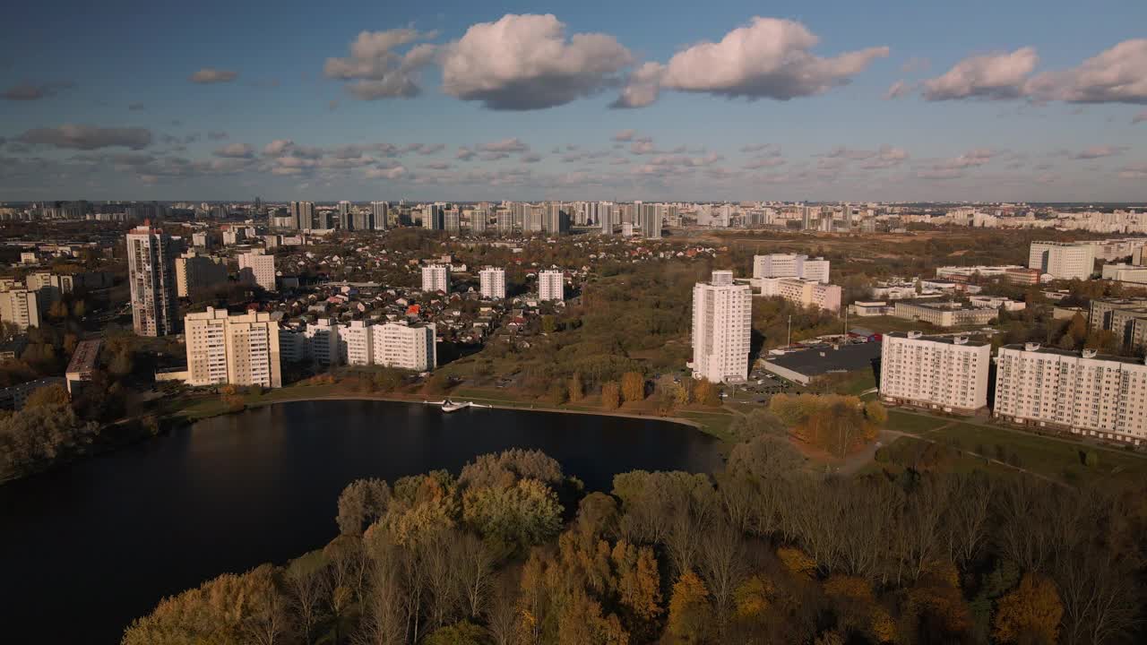 飞越秋天的公园。秋叶黄黄的树木随处可见。在地平线上有蓝色的天空和城市的房屋。公园的湖面清晰可见。航空摄影。视频素材