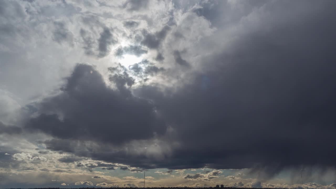 蓝云在雨天快速移动。阳光透过风暴自然环境黑暗巨大的乌云密布的天空镜头闪耀，天气预报雷雨云朵舞动全景地平线视频素材