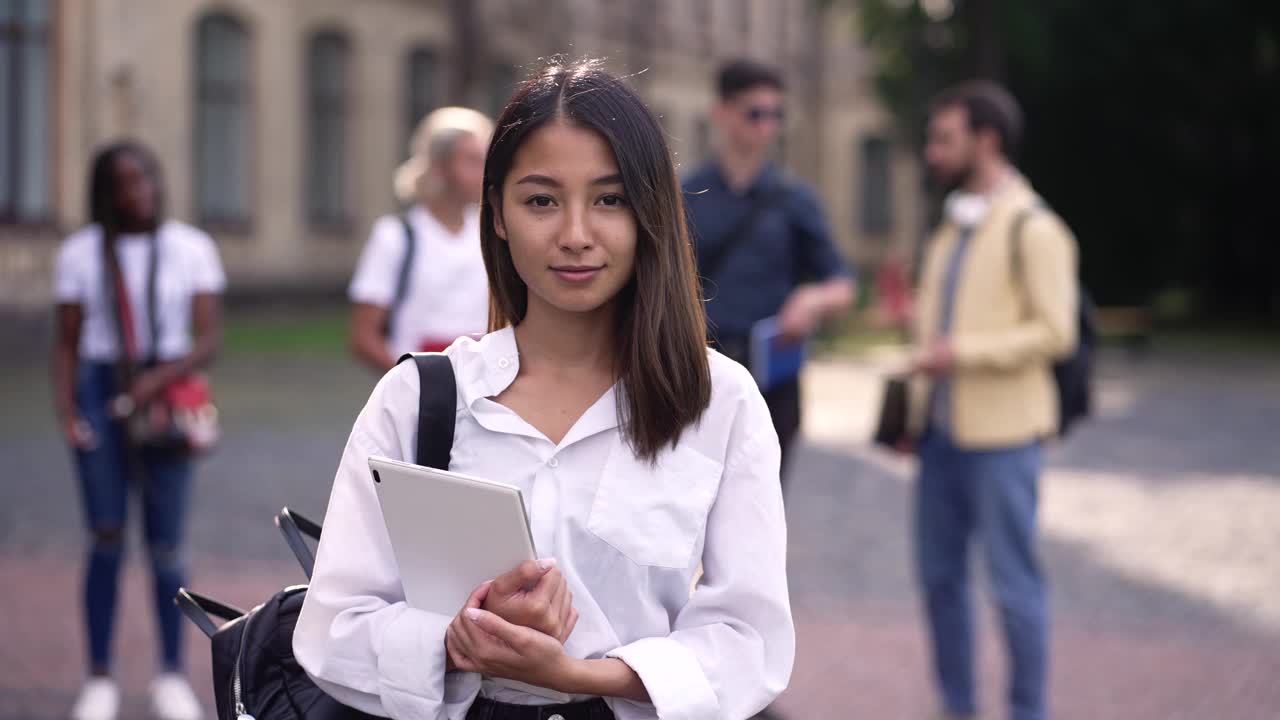 微笑的亚洲女学生在校园公园摆姿势视频素材