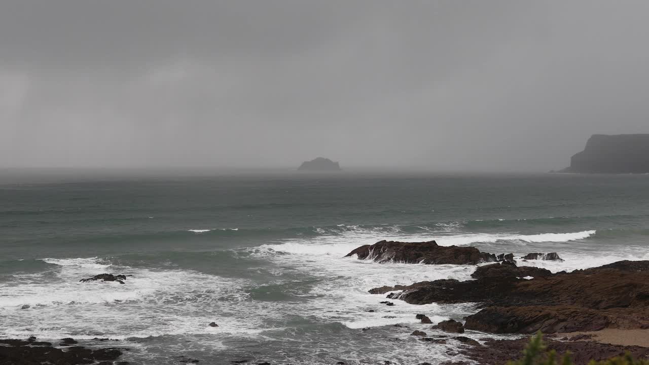 海上地平线上的雨云，与海浪拍打着海岸线上的岩石，有着复制的空间视频素材