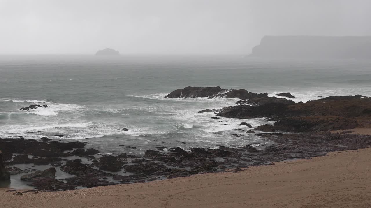 海上地平线上雨云密布，海浪拍打着海岸线上的岩石视频素材