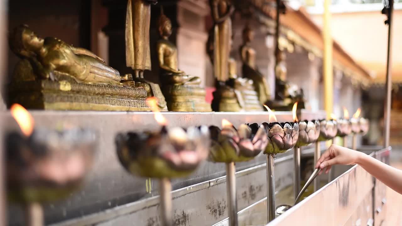 泰国清迈，素贴(Doi Suthep)，一名妇女在为拜佛用的银油灯加油视频素材