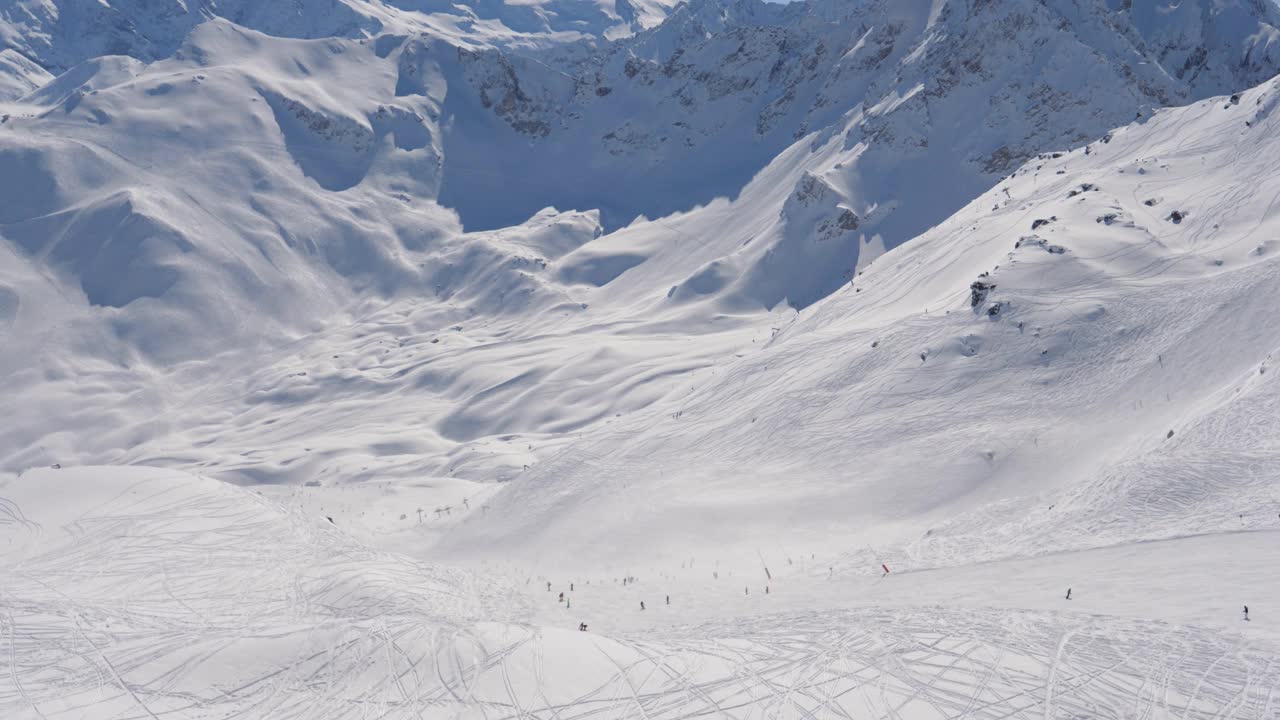 许多滑雪者和单板滑雪者在冬季从雪山的滑雪坡滑下视频素材