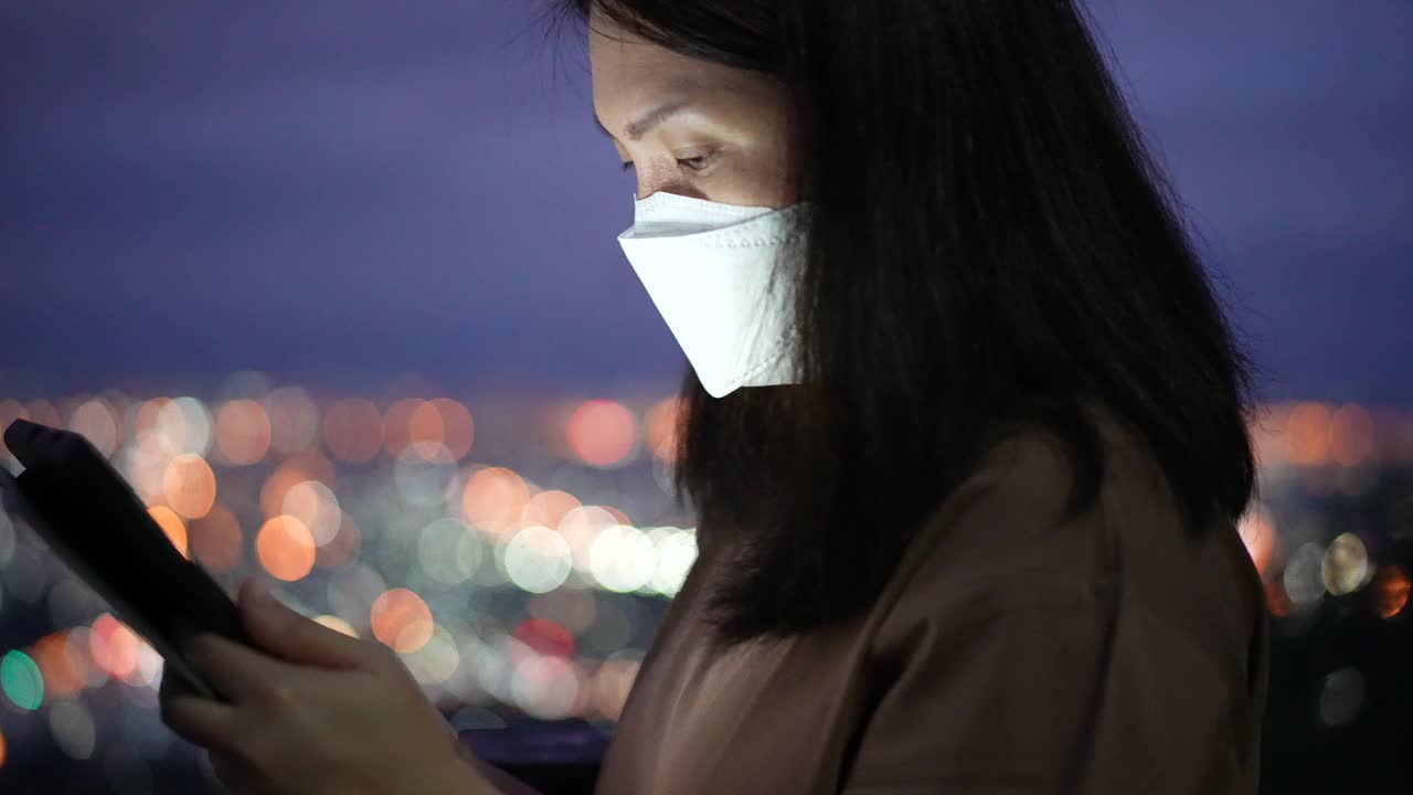 女人在夜里用手机用圆灯散景在城里视频素材