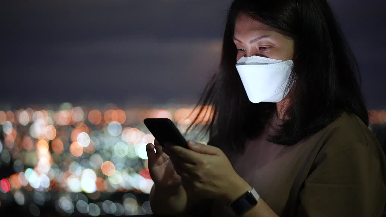 女人在夜里用手机用圆灯散景在城里视频素材