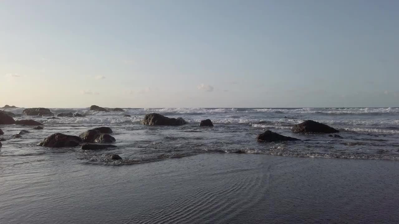 海滩和海洋地平线-低角度，小波浪在黑色沙滩上视频素材