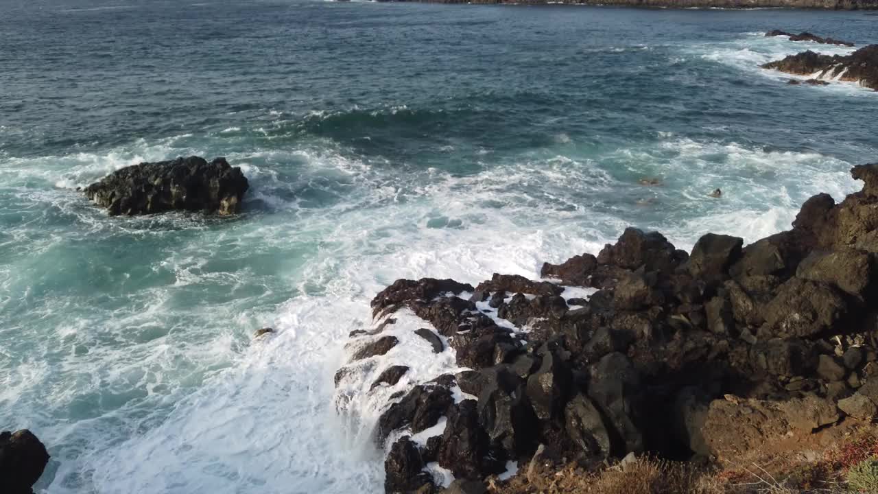 海浪拍打着黑色的石头，汹涌的海浪拍打着岩石视频素材