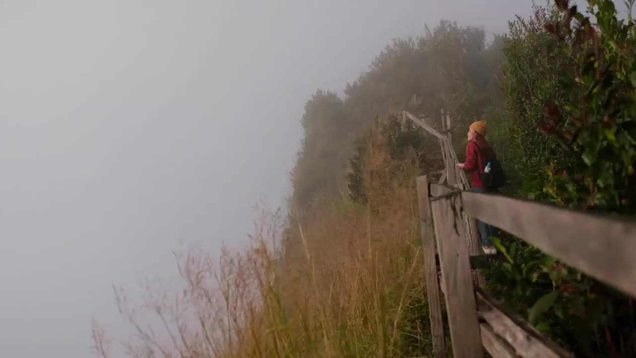 一个女旅行者在雾天看一座美丽的山的慢镜头视频素材