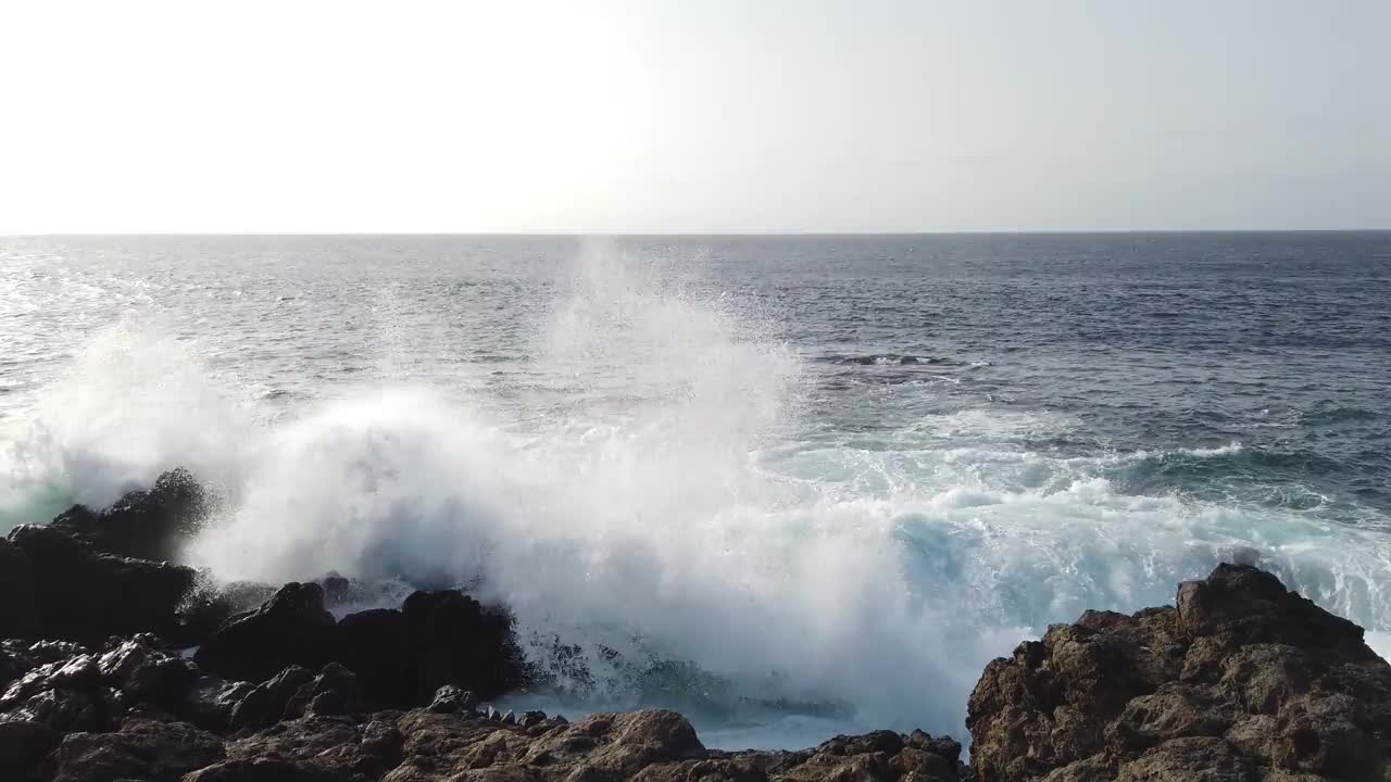 海浪拍打着黑色的石头，汹涌的海浪拍打着岩石视频素材