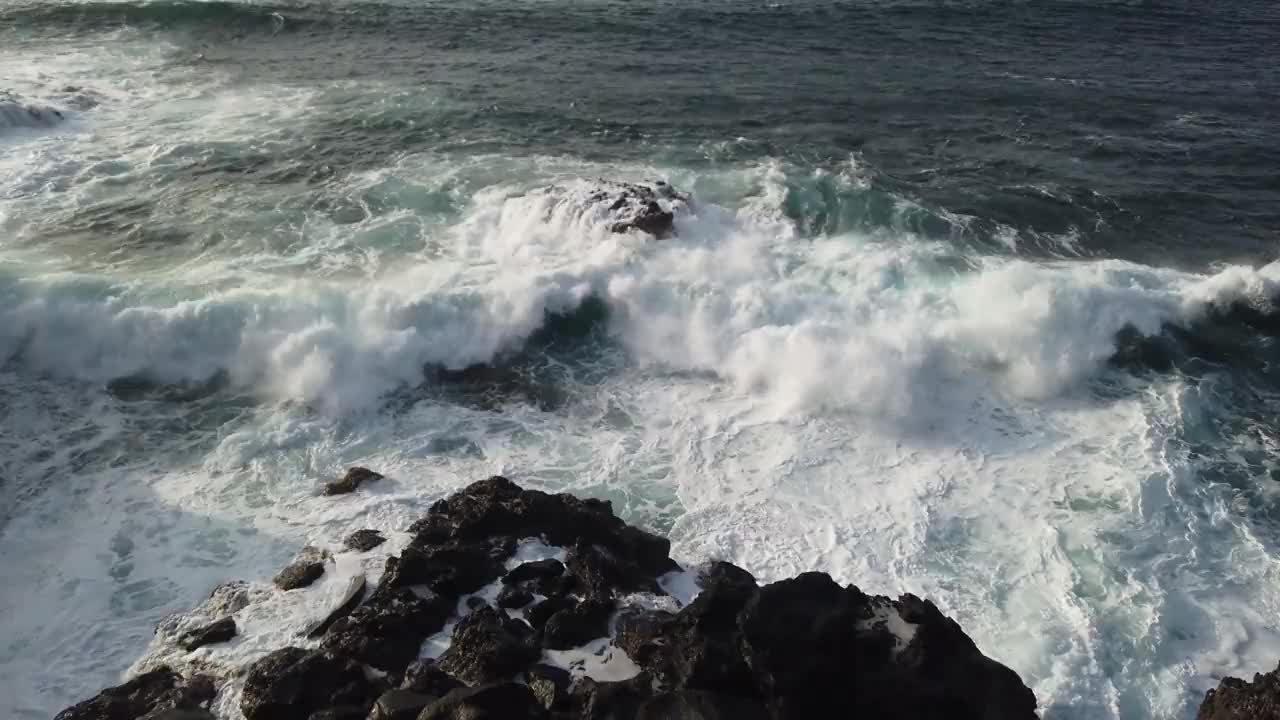 海浪拍打着黑色的石头，汹涌的海浪拍打着岩石视频素材