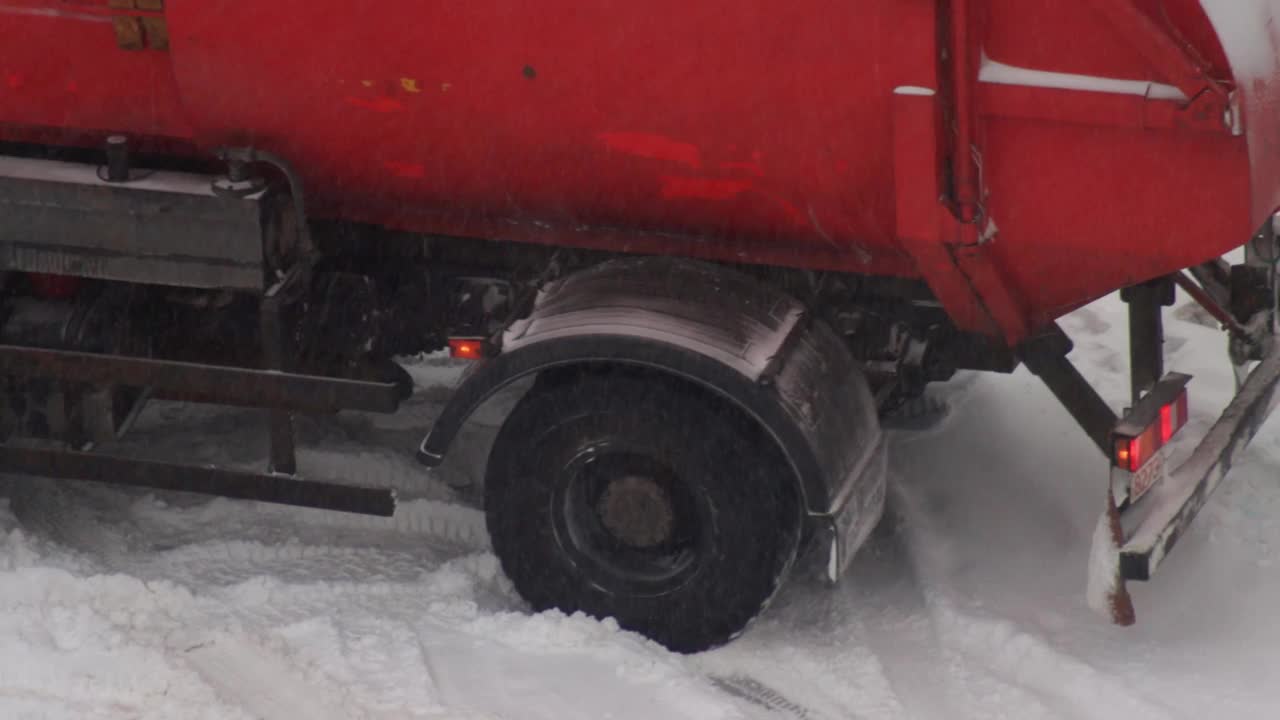 一辆垃圾车停在了冰上的雪地上。冬天的暴风雪，旋转，特写镜头。视频素材