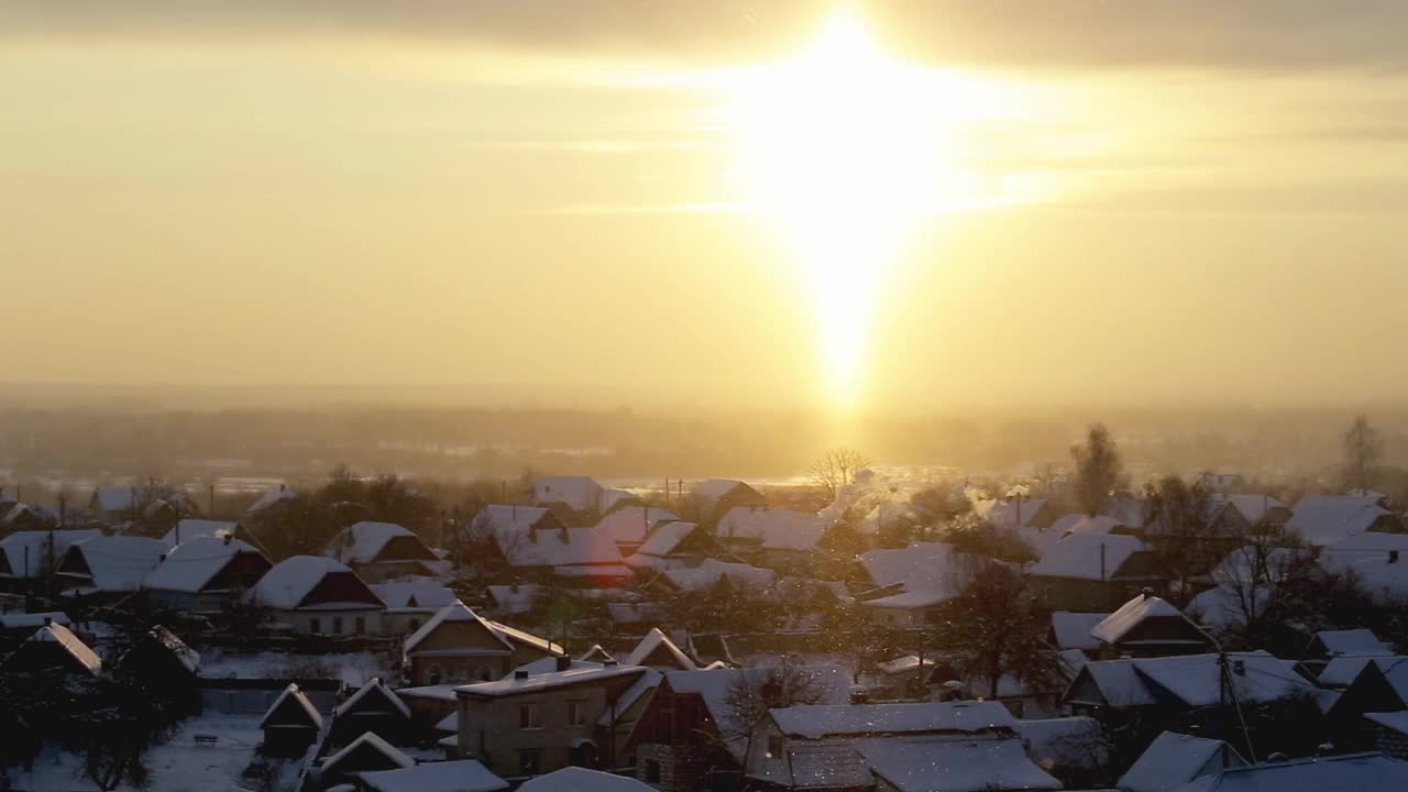 橙色的日出在一个霜冻的冬日早晨，以村庄为背景。美丽的天空和雪花视频素材