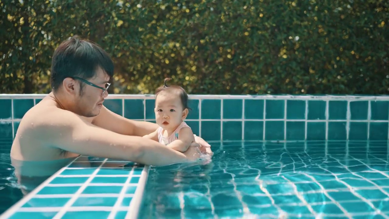 顶视图亚洲年轻的成年父亲非常快乐，享受与女儿在小游泳池游泳(3-7个月)的家庭生活视频素材