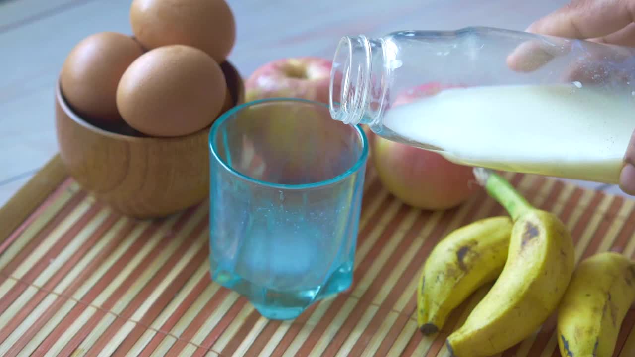 鸡蛋呈弓形，牛奶倒在玻璃杯里视频素材