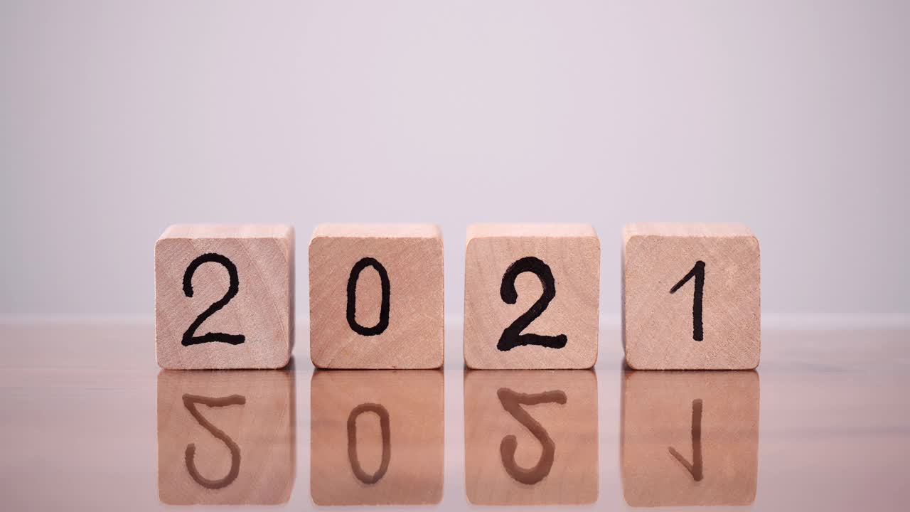 将2021年底改为2022年。从2021年到2022年，近距离观察男子手部翻转或翻转木块的变化。圣诞快乐，新年快乐。视频素材