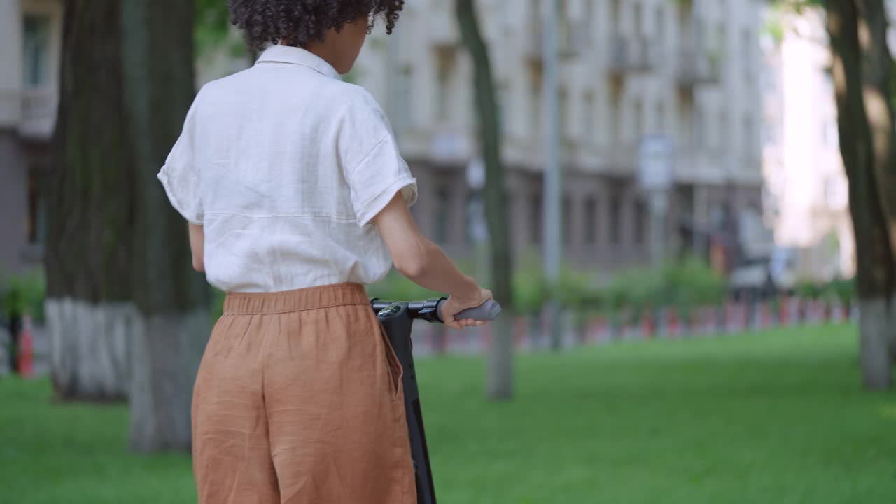 年轻的卷发女子骑着电动车在街上休闲活动视频素材