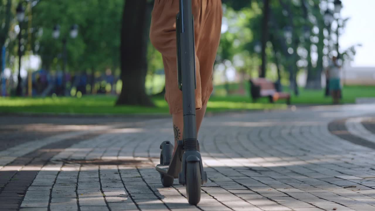 一名非洲裔美国女性完成电动滑板车的骑行，并为租赁应用拍照视频素材