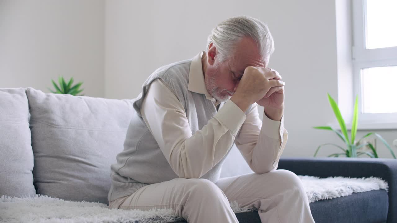 伤心的男士坐在家里的沙发上，想着问题，男士的健康视频素材