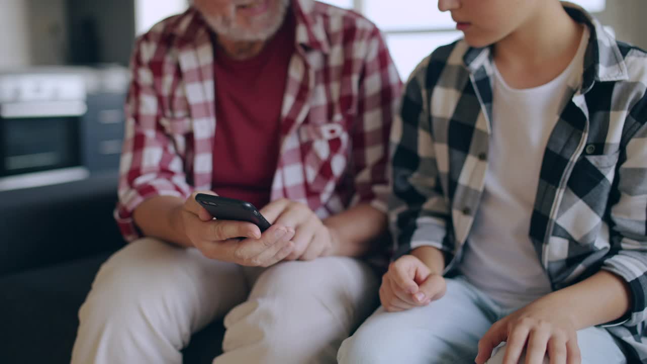 孩子向爷爷奶奶解释如何在智能手机上使用社交网络应用视频素材