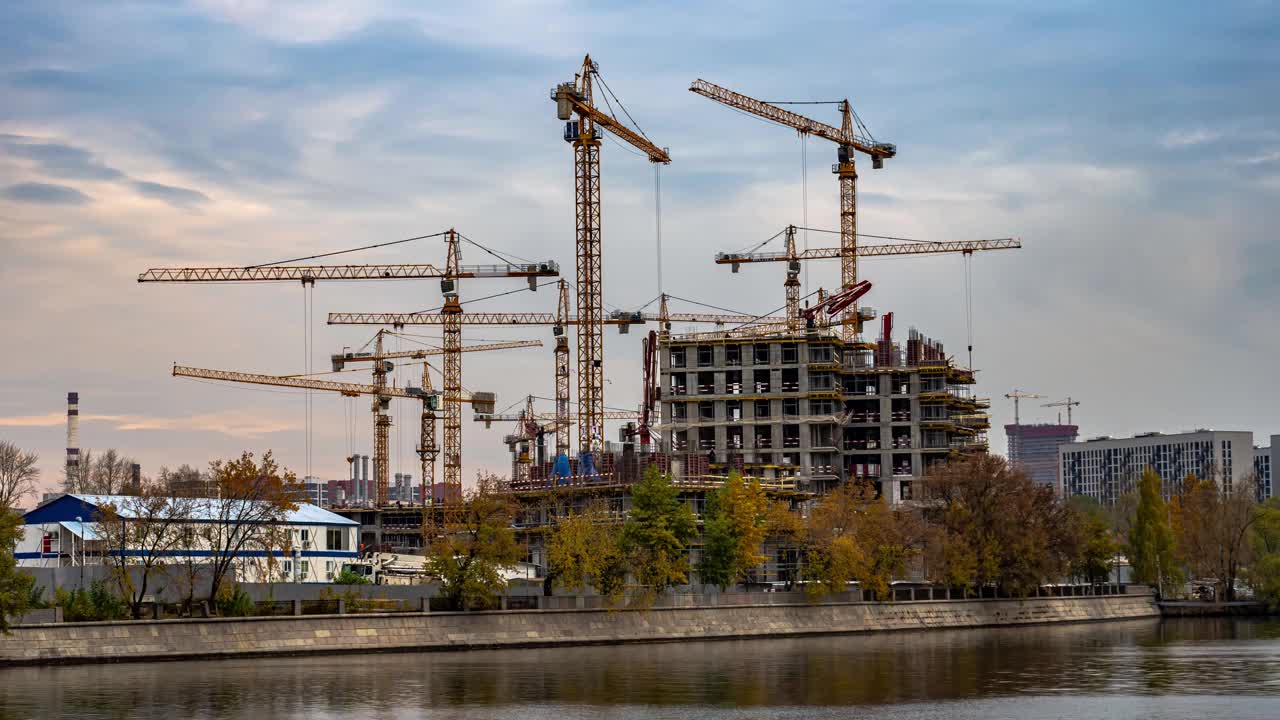 随着时间的推移，建筑起重机正在前工业区的河岸上建造一个住宅区视频素材