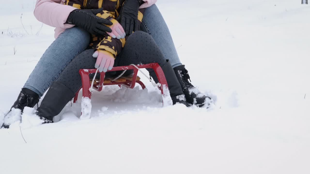 妈妈和女孩坐在雪橇上。视频素材