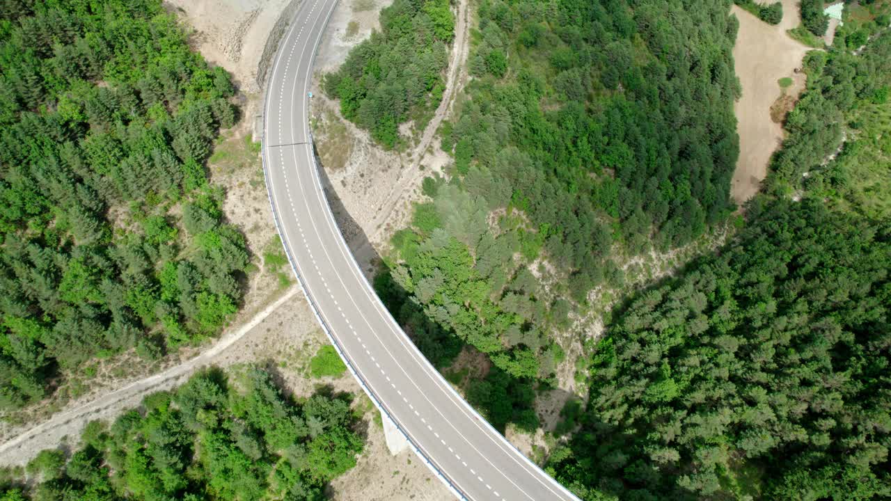 一座桥，一座山间的现代高架桥，一条三车道的柏油路。钢筋混凝土码头结构的桥梁连接两座小山，山上覆盖着森林。视频素材