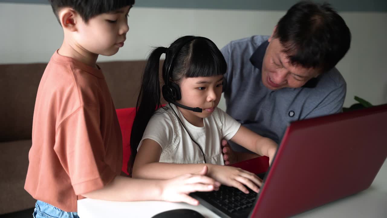 小女孩戴着耳机，在家里用笔记本电脑上网学习视频素材