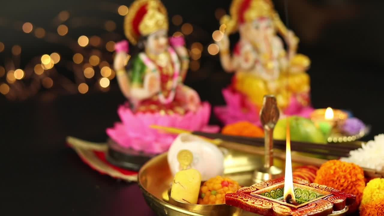 方形粘土Diya Deep或Dia Lit In Puja Thali With Ganesha Lakshmi Laxmi In Background。穿Choodi衣服的女孩的手放着卡拉什和水果。Dussehra Puja的主题，Shubh Deepawali视频素材