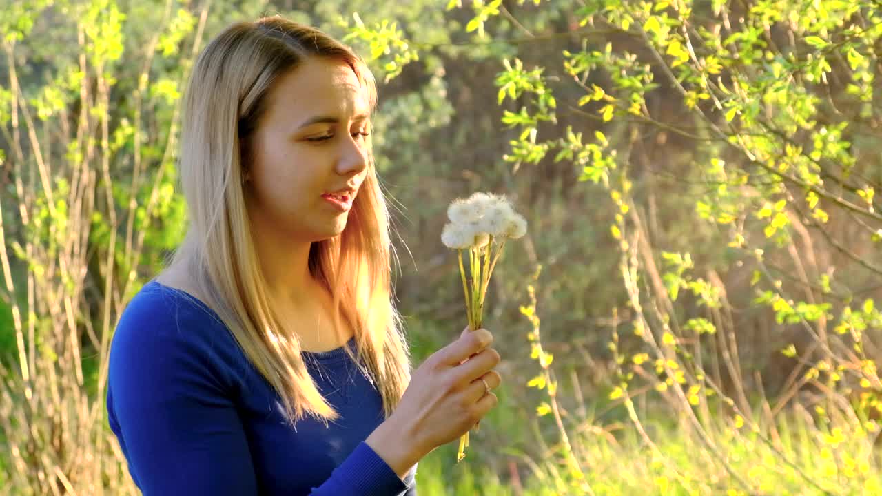 女孩吹着蒲公英的花。有选择性的重点。视频素材