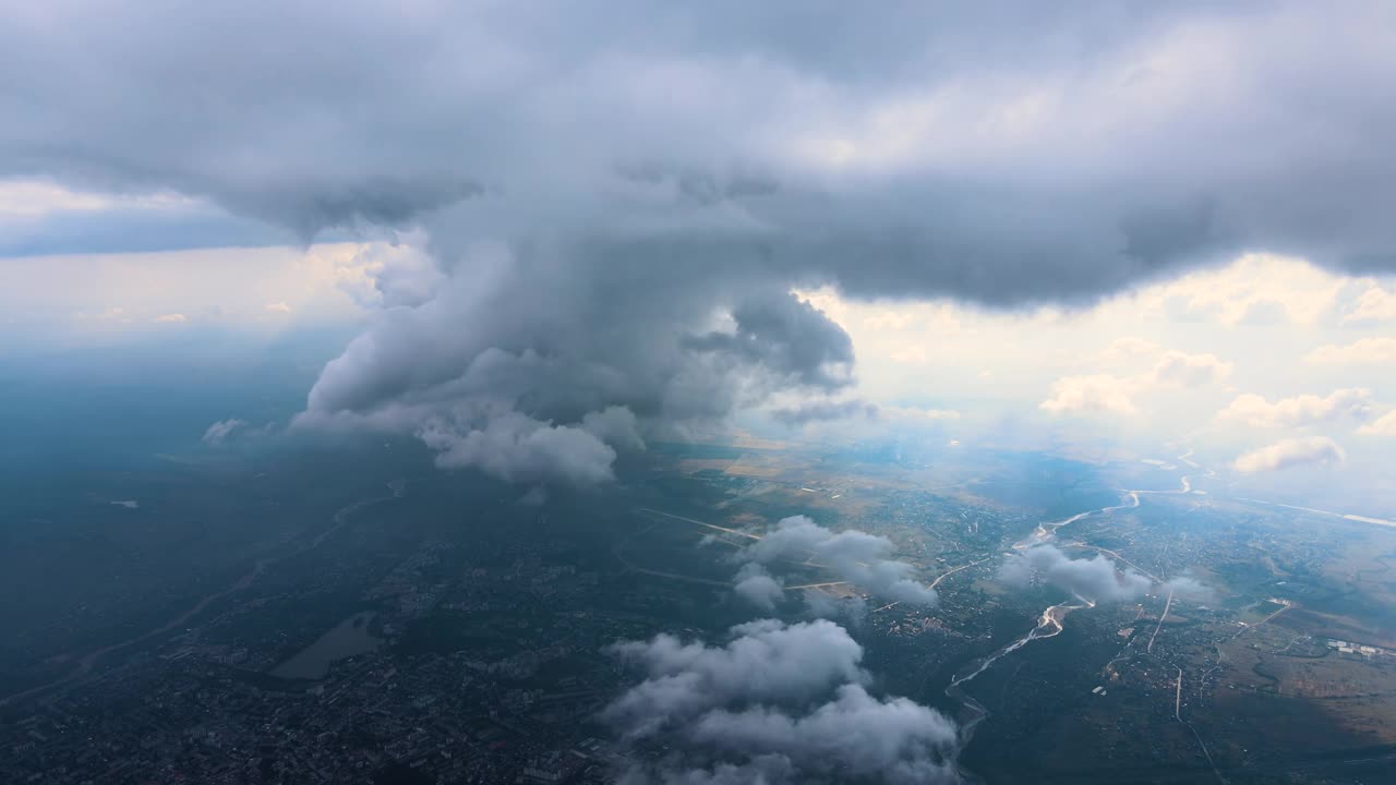 从高空的飞机窗口鸟瞰图，远处的城市被暴雨前形成的蓬松积云所覆盖。视频素材