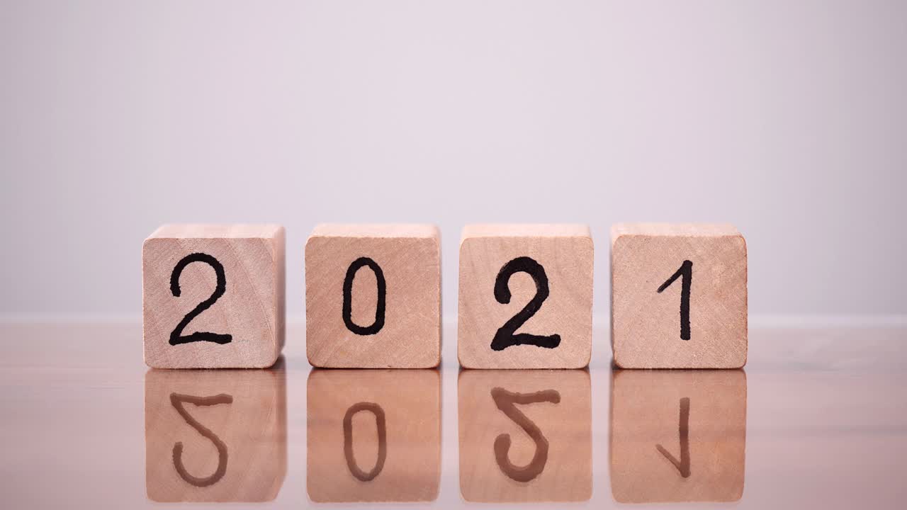 将2021年底改为2022年。从2021年到2022年，近距离观察男子手部翻转或翻转木块的变化。圣诞快乐，新年快乐。视频素材