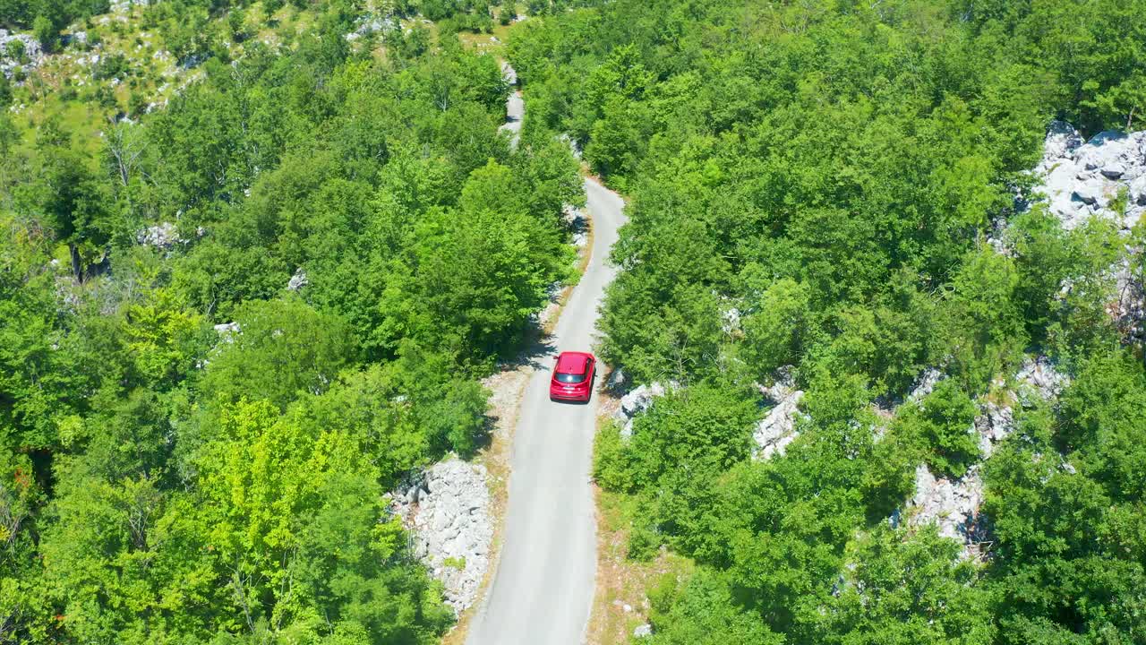 无人机到道路与红色汽车通过森林与弯道的鸟瞰图。视频素材