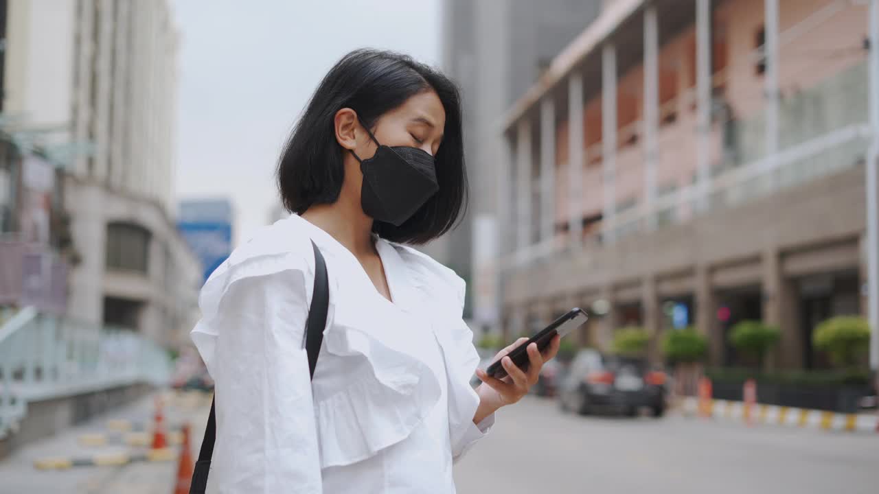 亚洲女商人在等出租车时使用手机视频素材