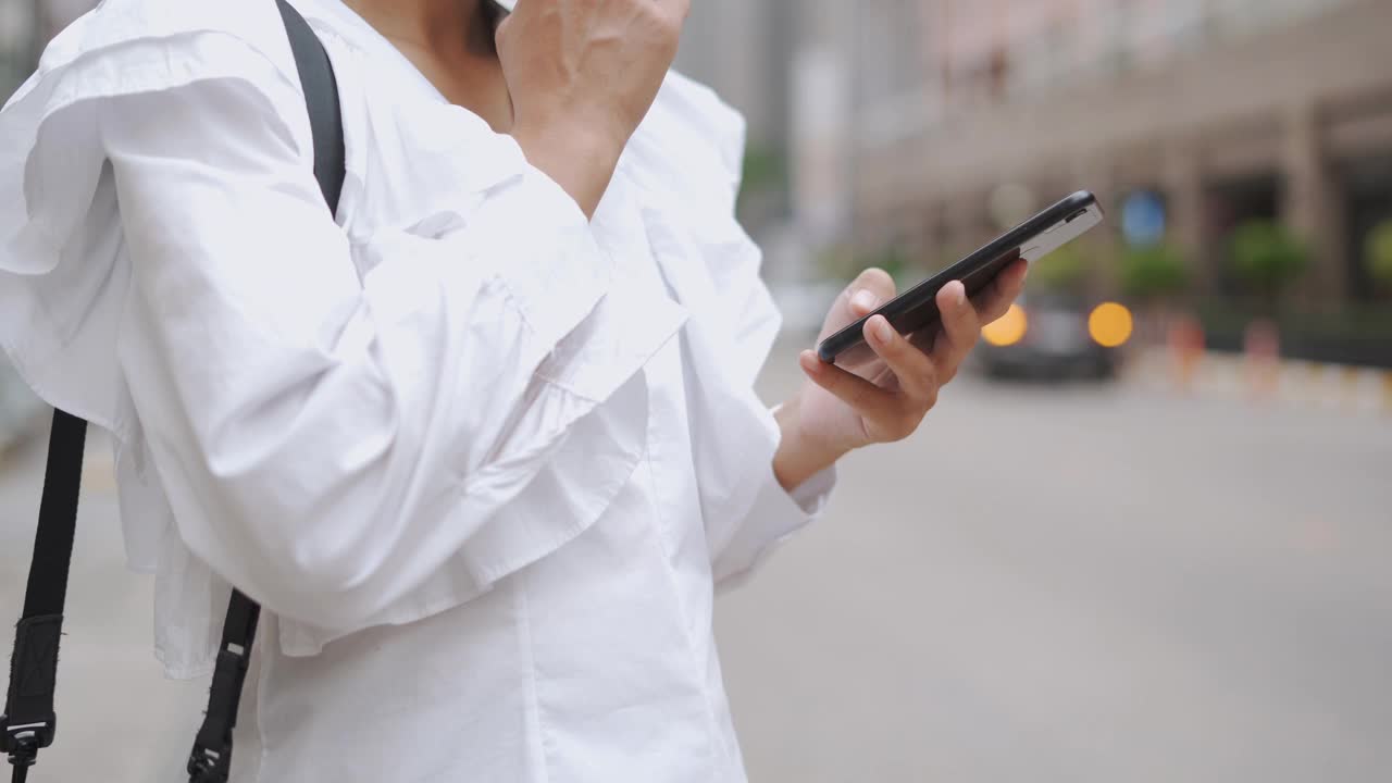 亚洲女商人在等出租车时使用手机视频素材