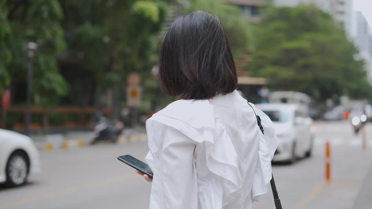 亚洲女商人在等出租车时使用手机视频素材